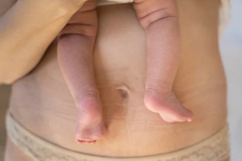 Đôi chân em bé được bế trước bụng mẹ