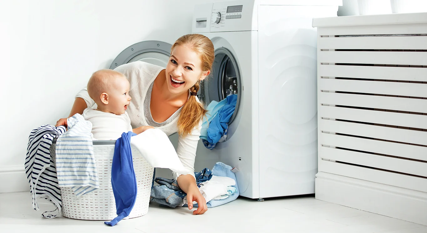 Mẹ và bé bên máy giặt với giỏ quần áo
