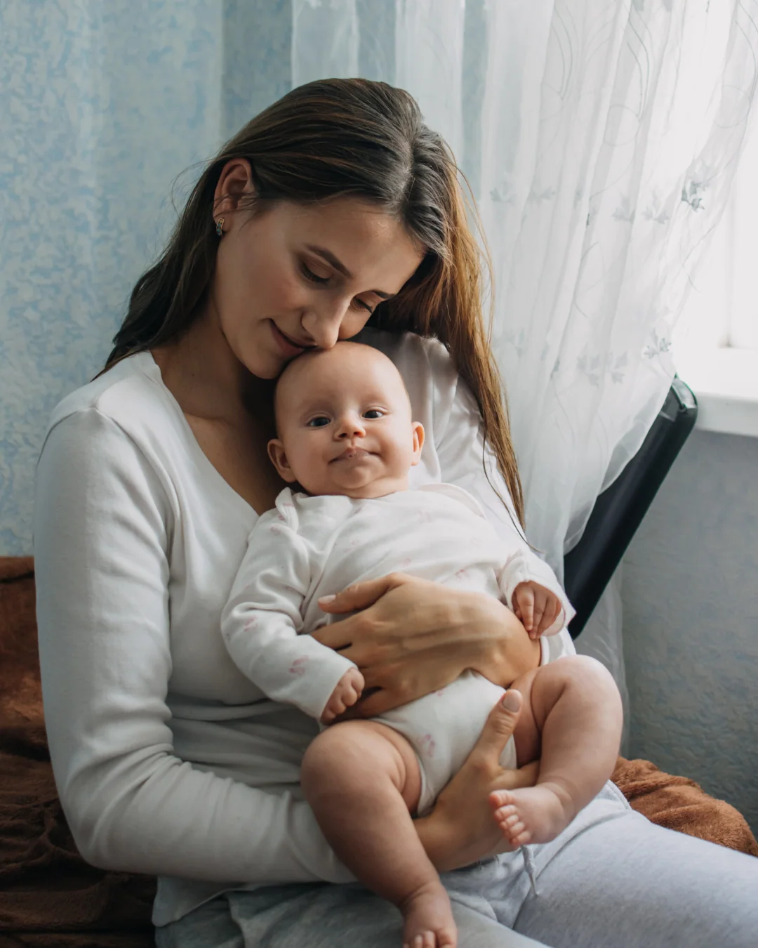 Mẹ ôm em bé bên cửa sổ
